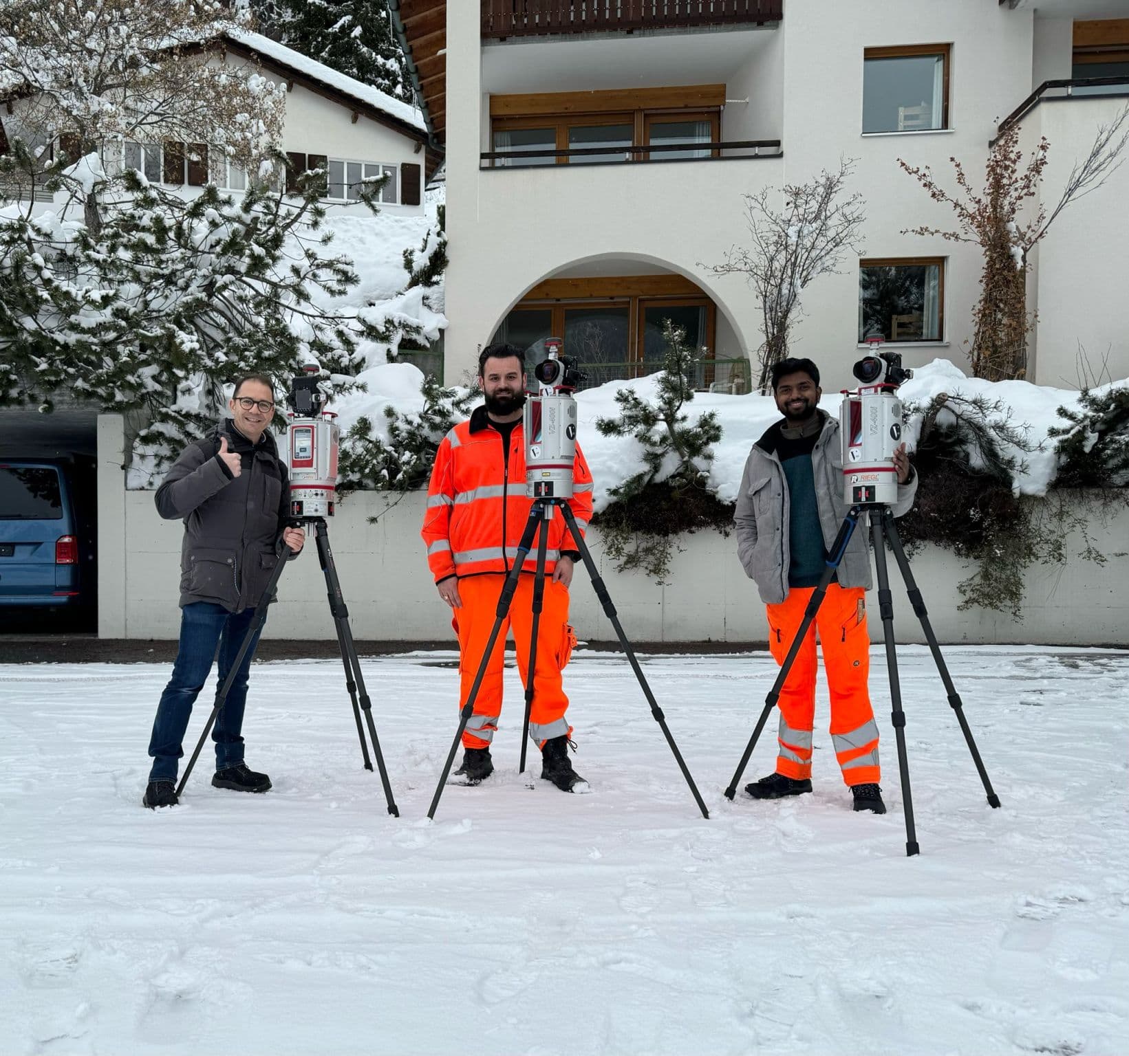 Drei Vermessungsingenieure mit Theodoliten im winterlichen Umfeld.