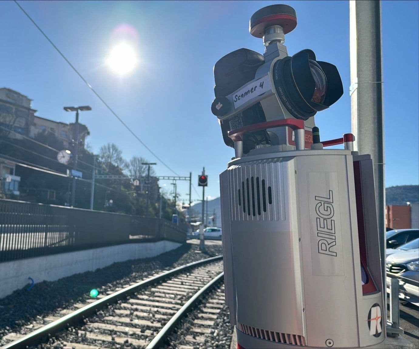 Vermessungsgerät von RIEGL neben Eisenbahnschienen bei sonnigem Wetter.