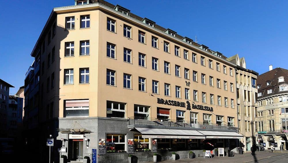 Eckgebäude in europäischer Stadt bei Tageslicht mit Restaurant im Erdgeschoss.